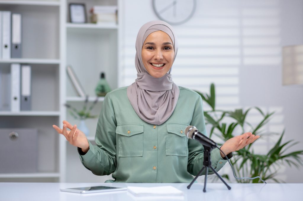Muslim woman in hijab hosting a podcast or web seminar from a modern office